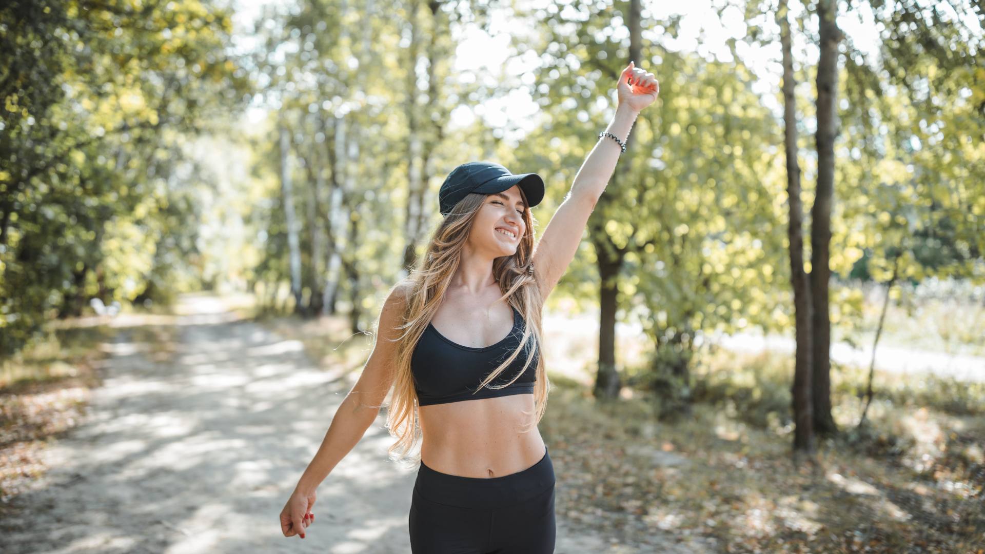 A woman wears black workout gear on a walk, demonstrating how to fast and become fasted adapted.